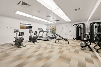 A gym with a variety of equipment including treadmills, weights, and exercise machines.